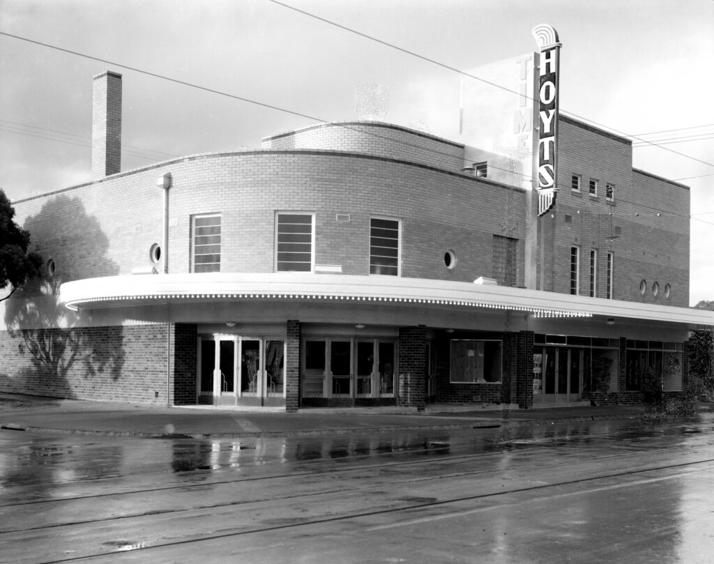 Black and white image of the Time Theatre in Balwyn, showing a sign saying 'Hoyts' looking across Whitehorse Road with tram tracks in the foregounrd.