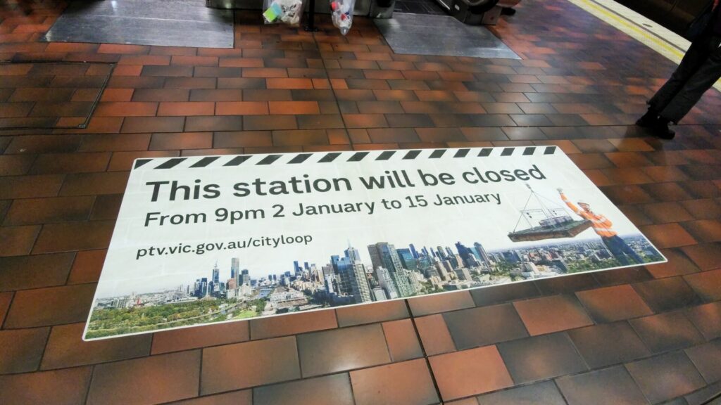 Photo of a large sign on the floor of Melbourne Central Station saying "This station will be closed from 9pm 2 January to 15 January ptv.vic.gov.au/cityloop".