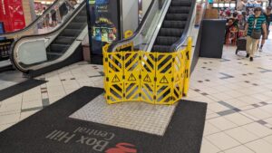 Photo of a broken escalator at Box Hill Shopping Centre with a yellow plastic fence around it.